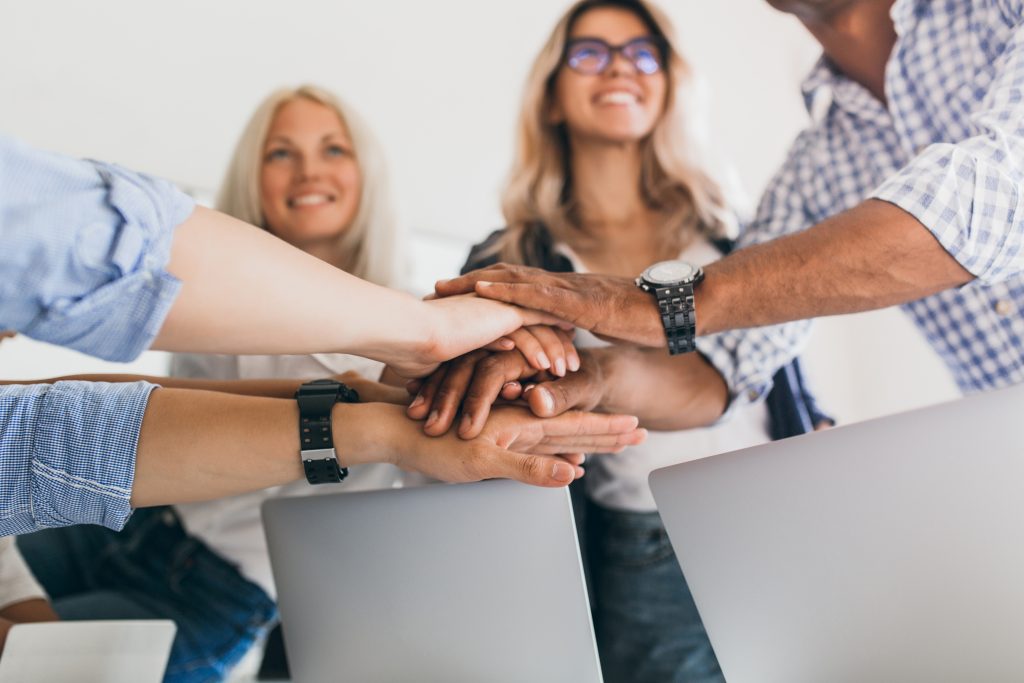 blonde female office worker looking up with smile while holding hands with colleagues indoor portrait friends ready start joint work project scaled