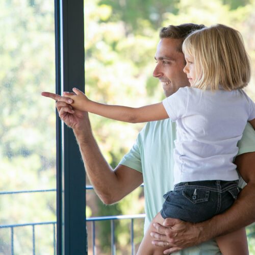 happy dad holding cute daughter pointing somewhere scaled